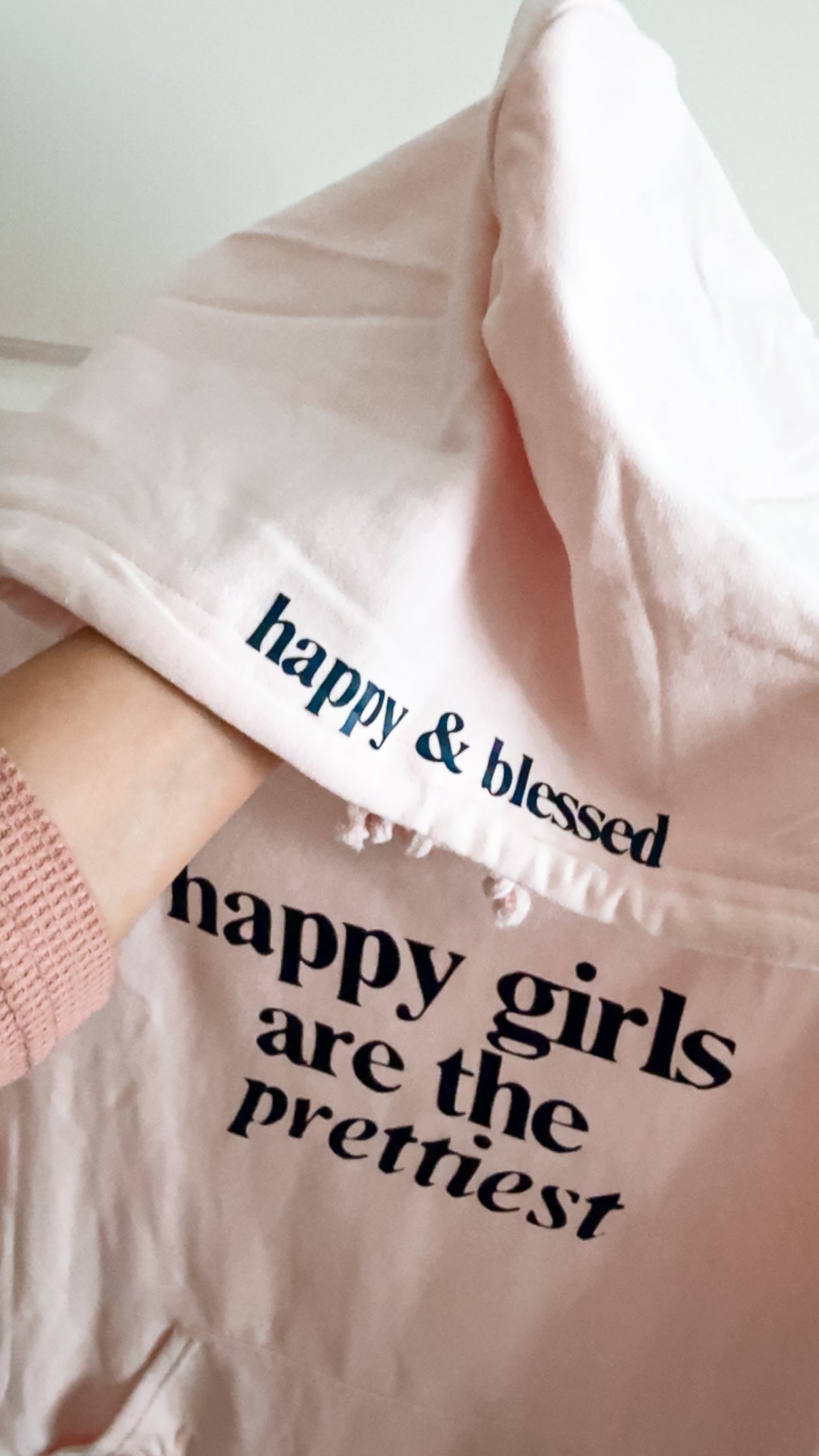 Pink sweatshirt with text 'happy & blessed happy girls are the prettiest' on a light background