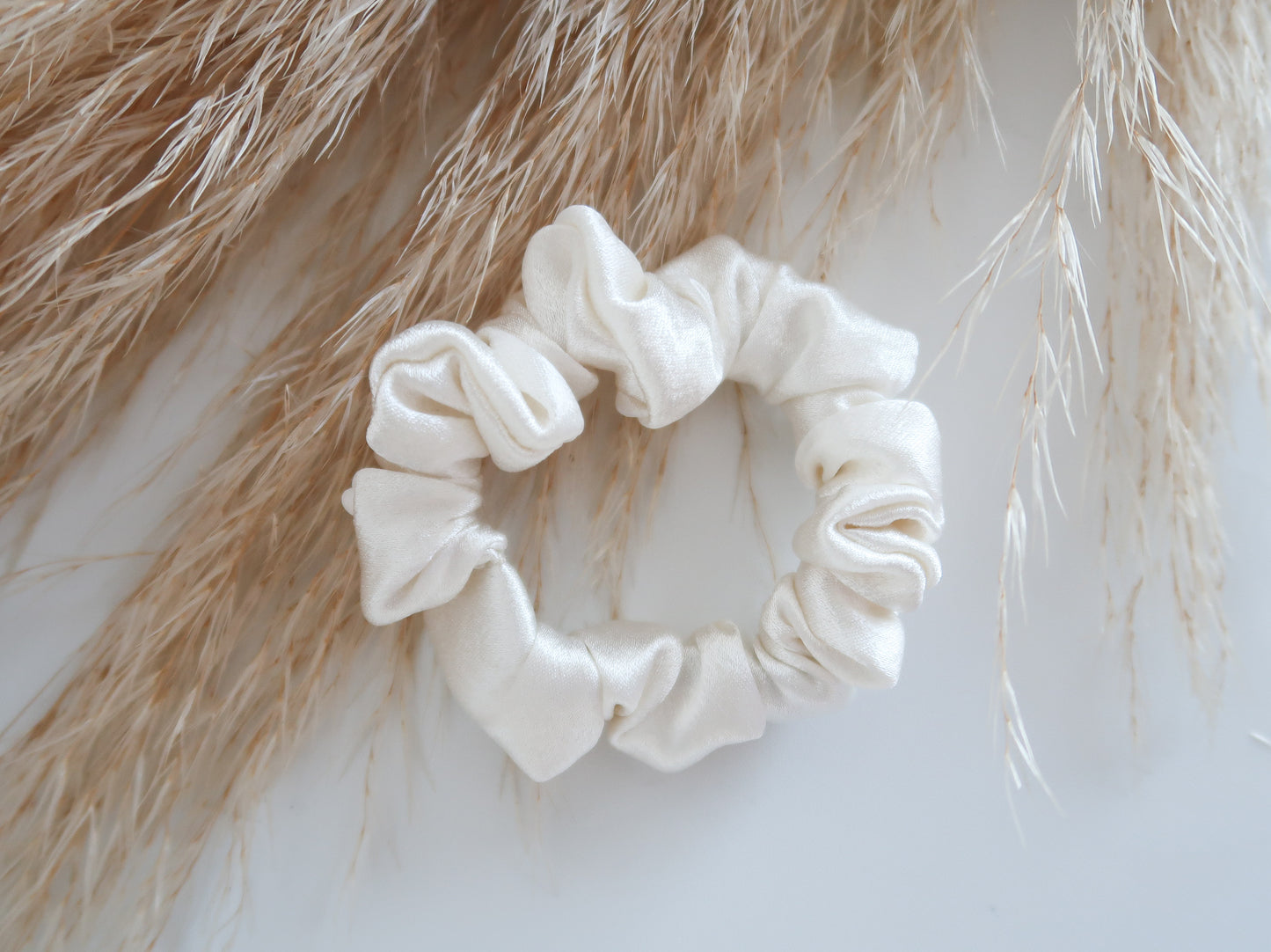 white scrunchie on a light background with dried grasses.