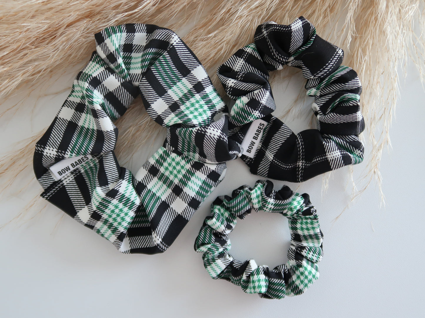 Three plaid scrunchies on a light wooden surface