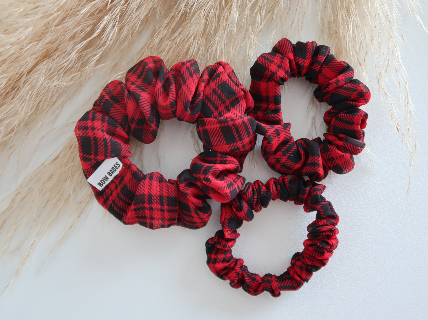 Red and black plaid scrunchies on a light wooden surface