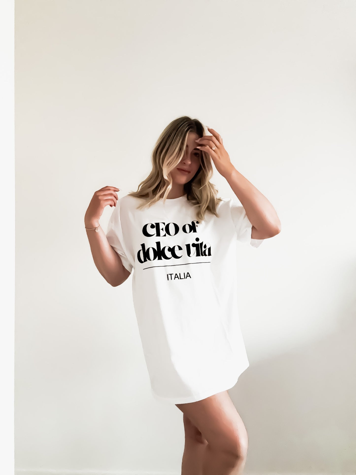 Woman wearing a white t-shirt with text, standing against a plain background