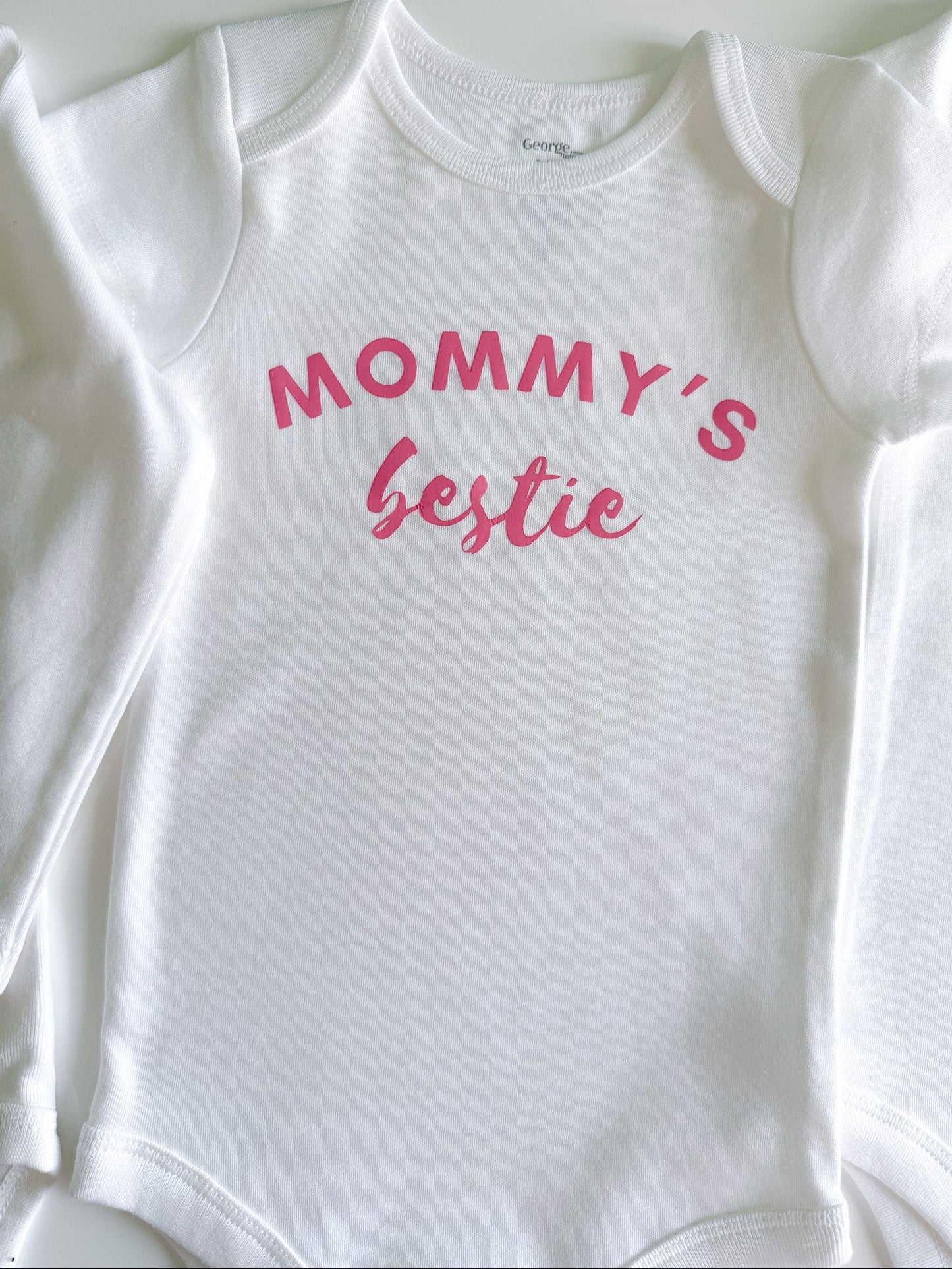 White baby onesie with pink text 'Mommy's Bestie' on a white background