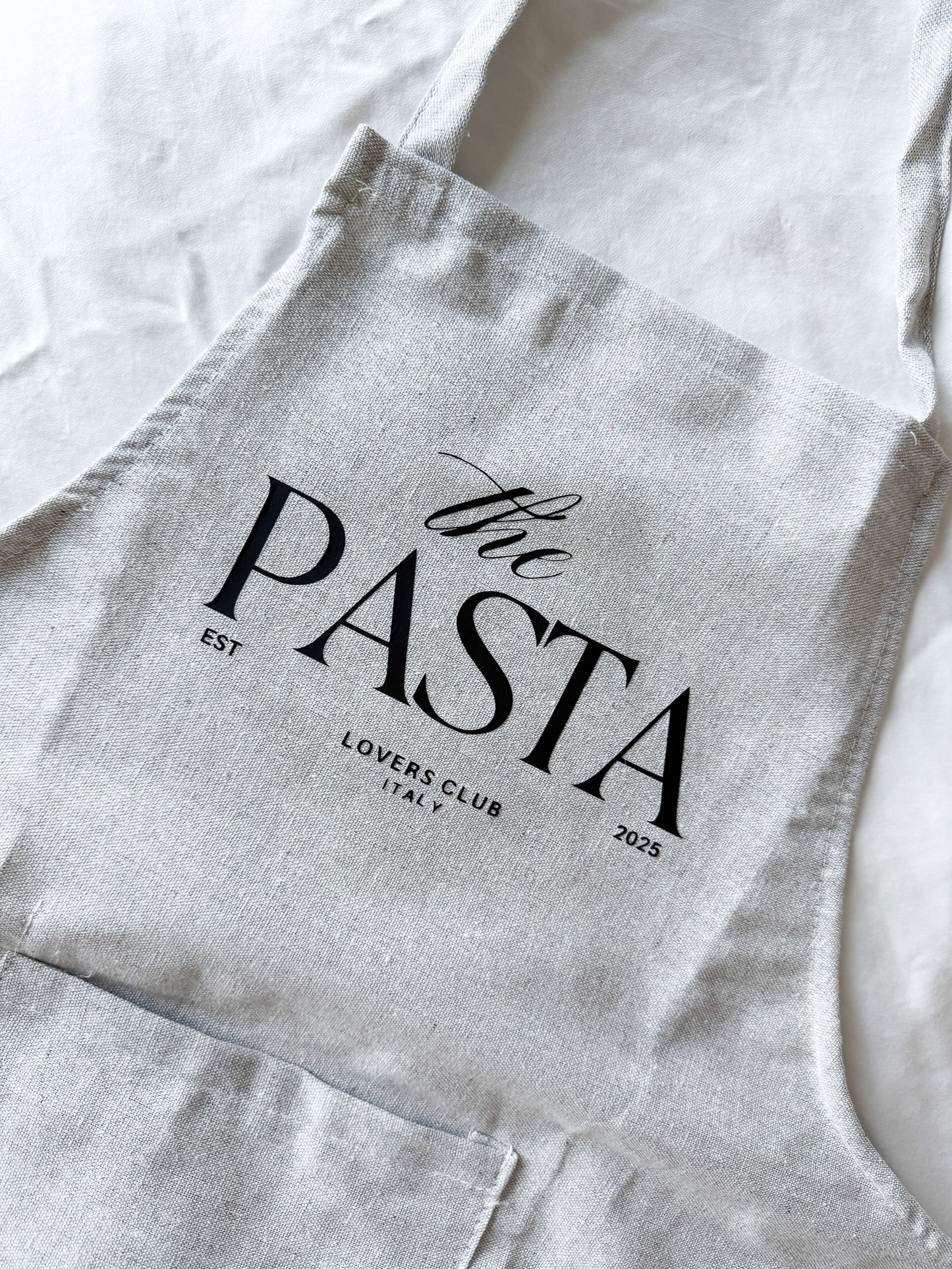 Gray apron with 'the PASTA LOVERS CLUB' text on a white background