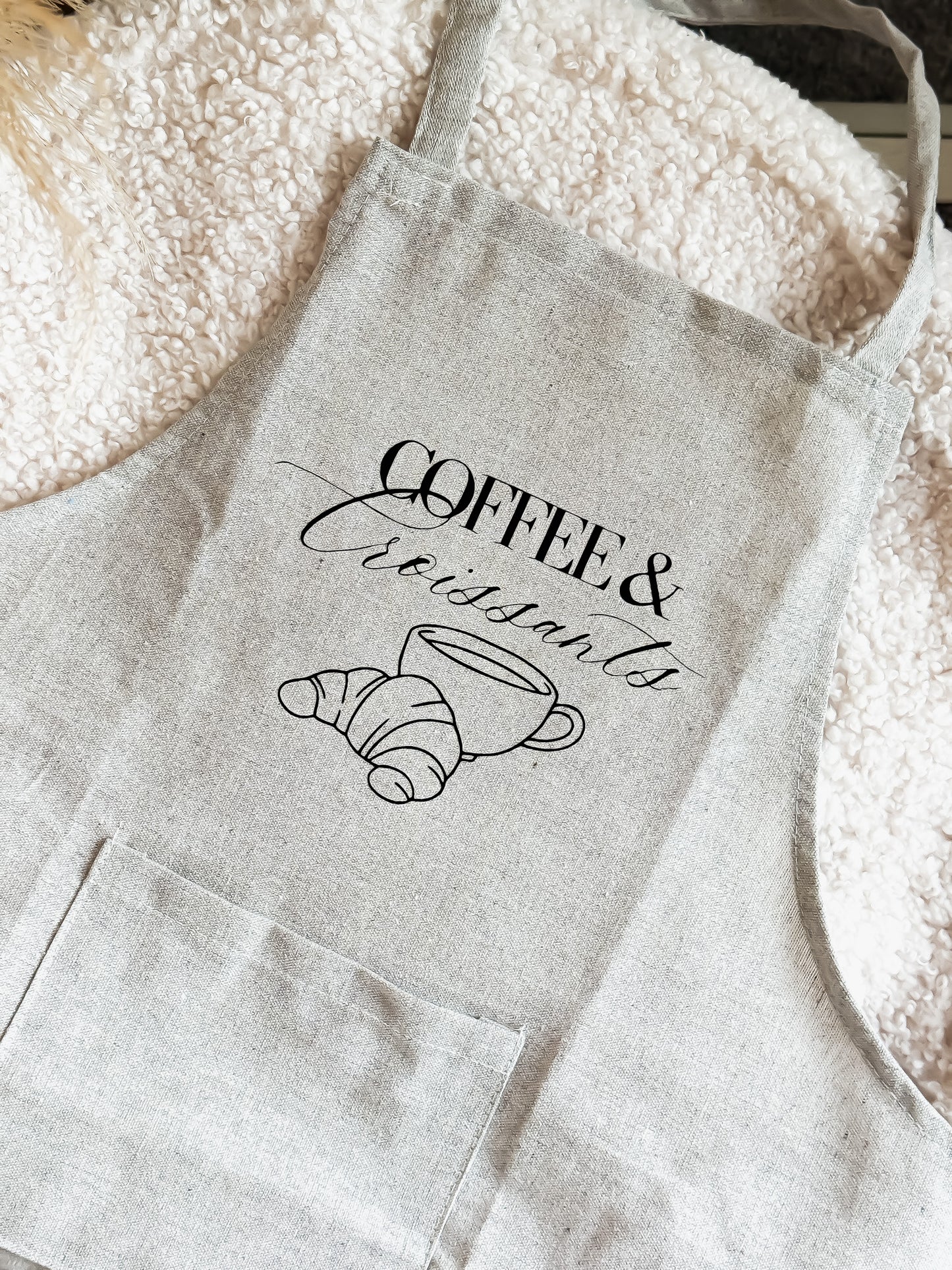 Light gray apron with 'Coffee & Croissants' text and cup illustration on a flour-dusted surface.