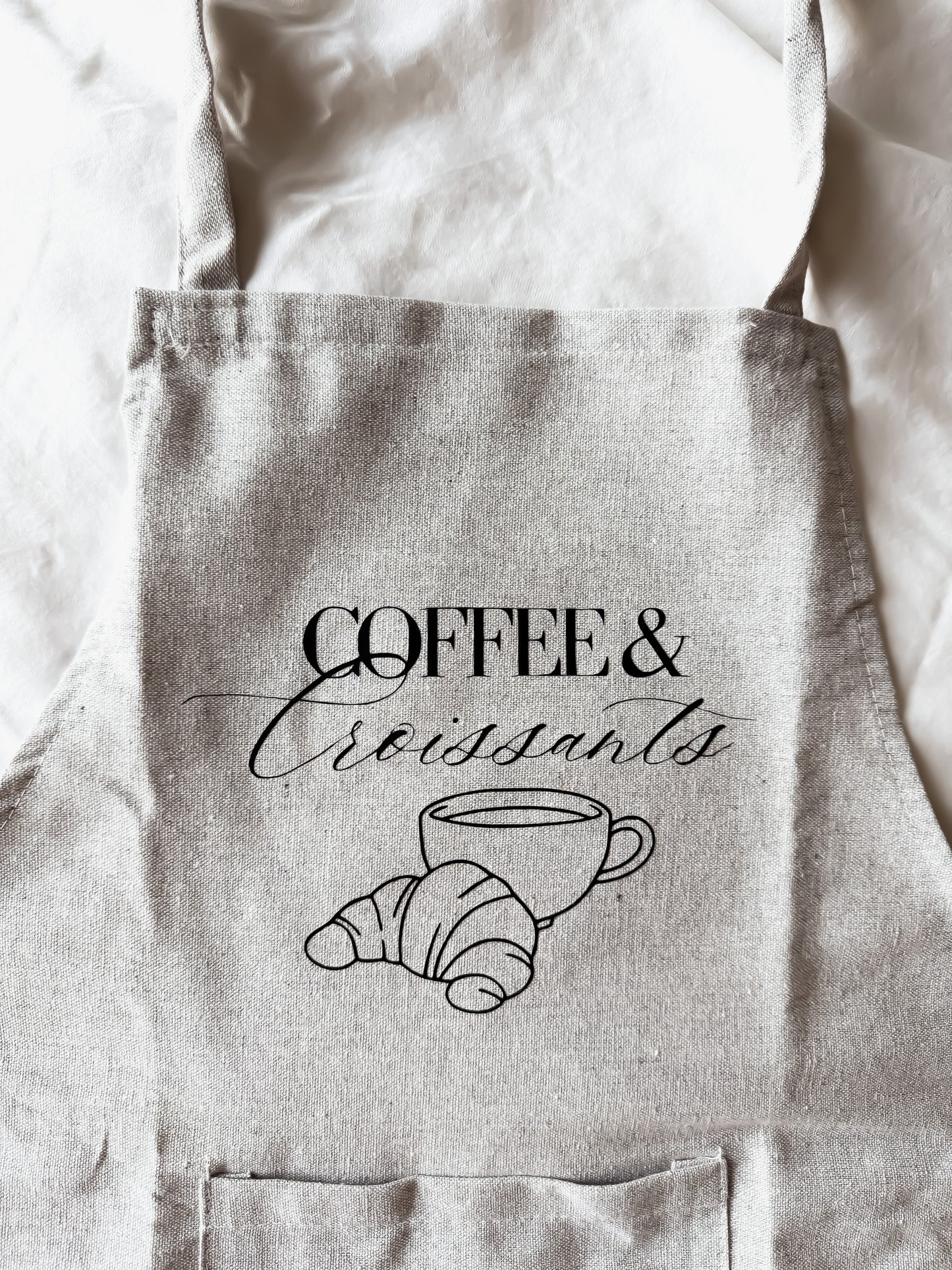 Light gray apron with 'Coffee & Croissants' text and graphics on a white background