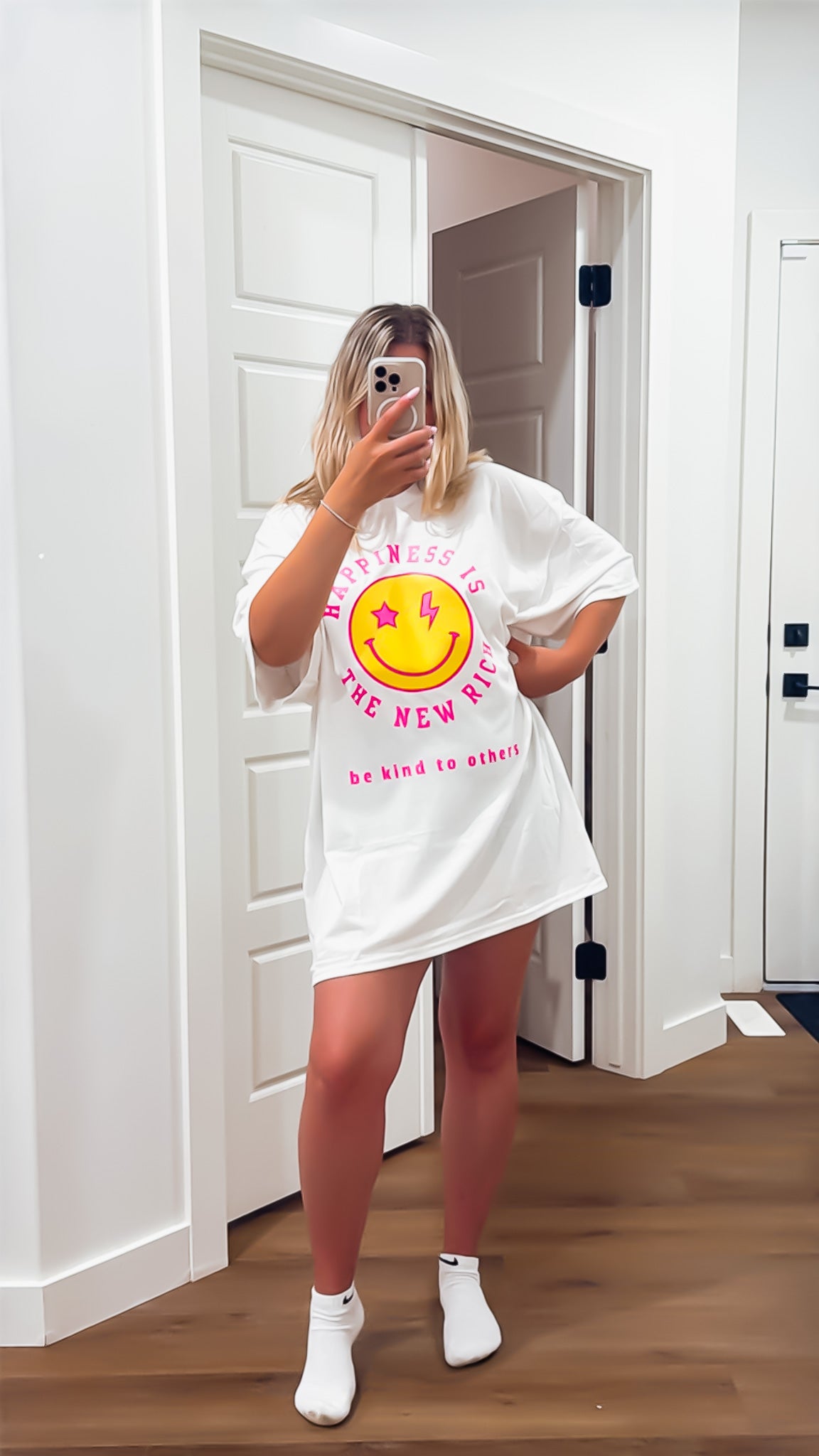 Person wearing a white oversized t-shirt with a graphic design in a room.
