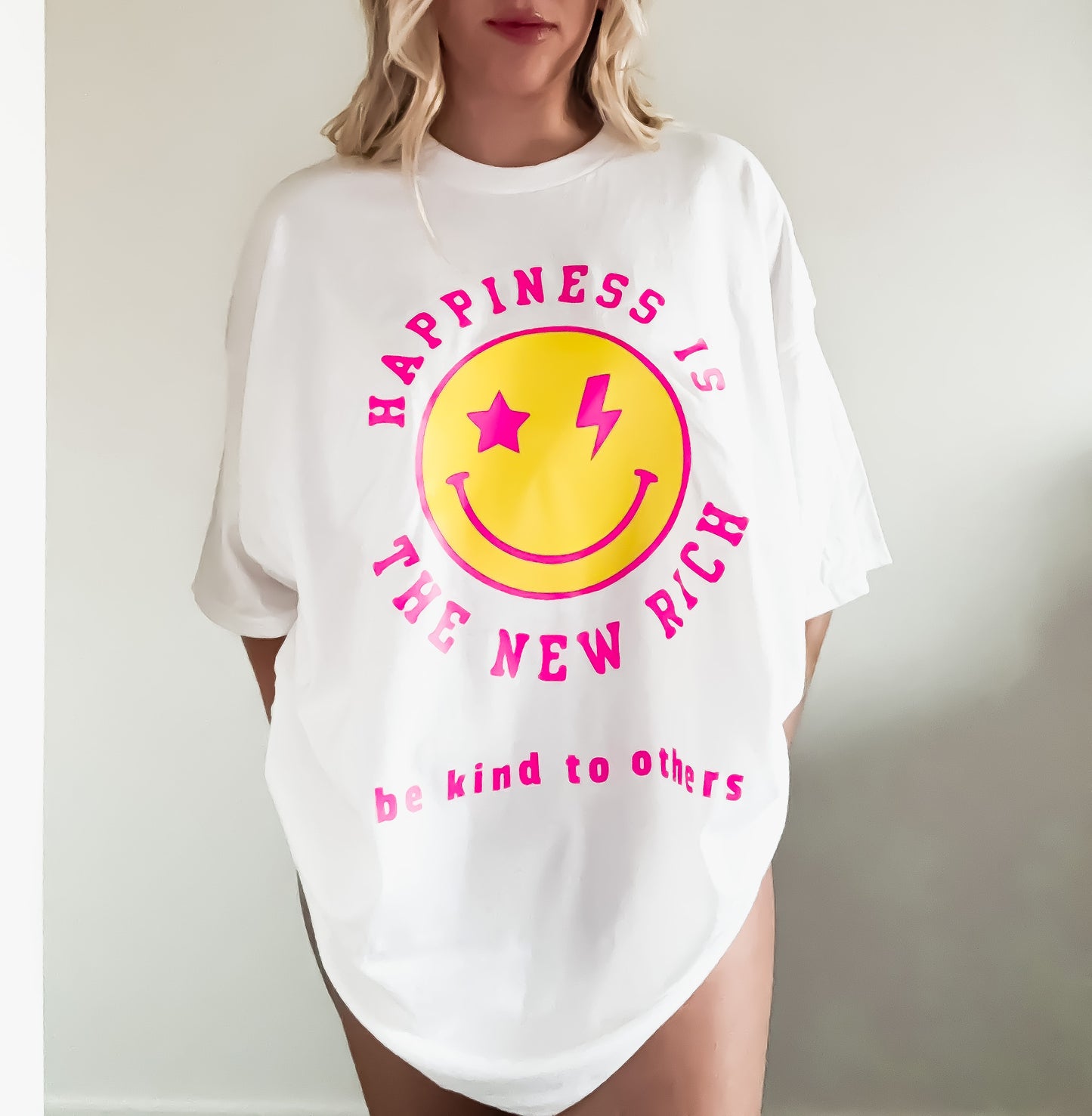 White t-shirt with a smiley face and text design worn by a person.