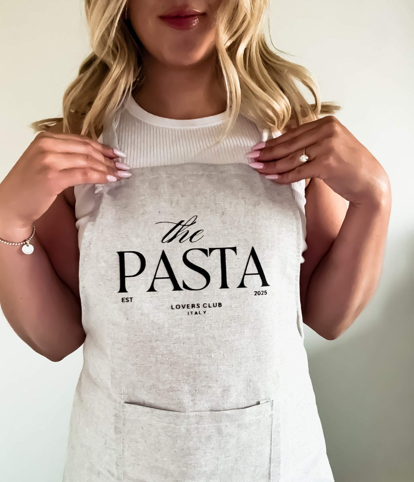 Person wearing a gray apron with 'the PASTA LOVERS CLUB' text.