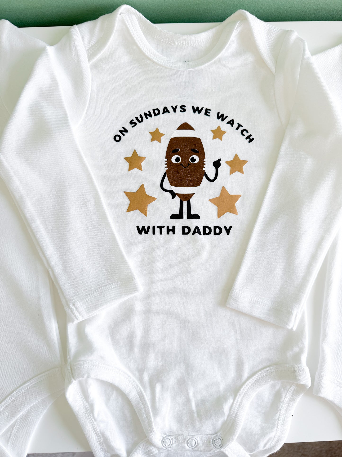 White baby onesie with a cartoon design and text on a white background
