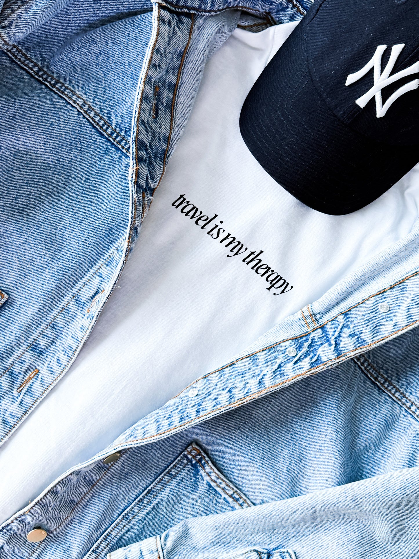 Denim jacket with 'reading is my therapy' tattoo and New York Yankees cap.