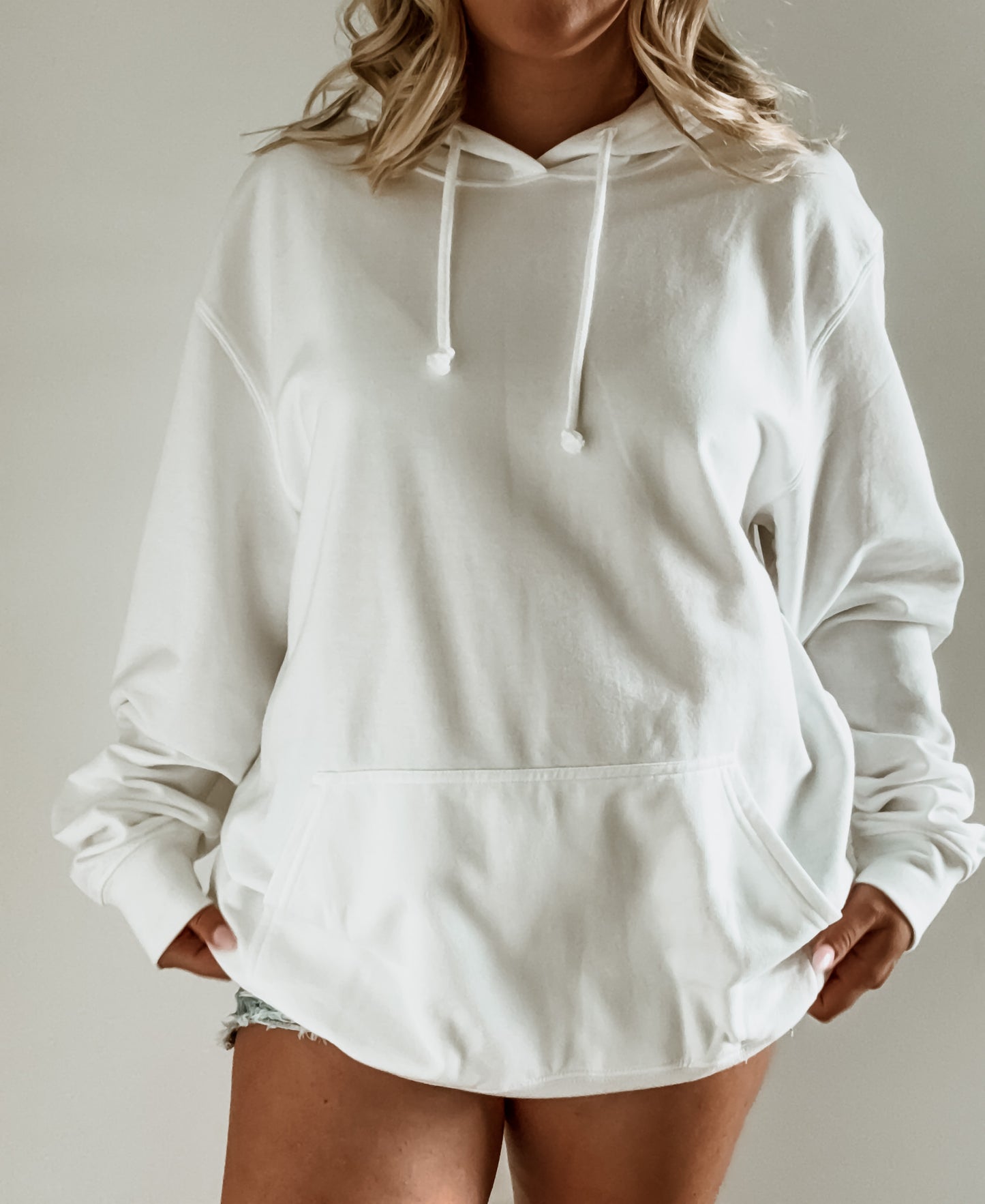 White hoodie worn by a person on a neutral background