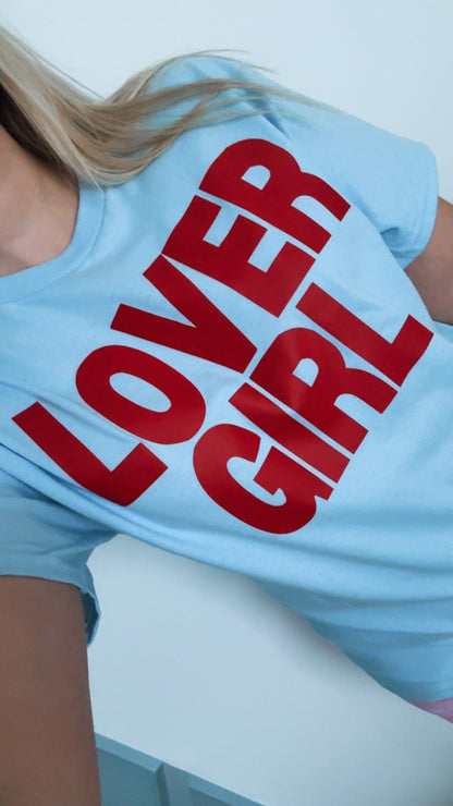 Light blue t-shirt with red 'LOVER GIRL' text worn by a person.