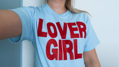 Person wearing a light blue t-shirt with 'LOVER GIRL' in red text.