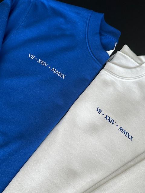 Blue and gray sweatshirts with embroidered text on a black background