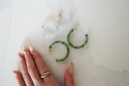Green sparkly resin hoop earrings paired with small clear earrings