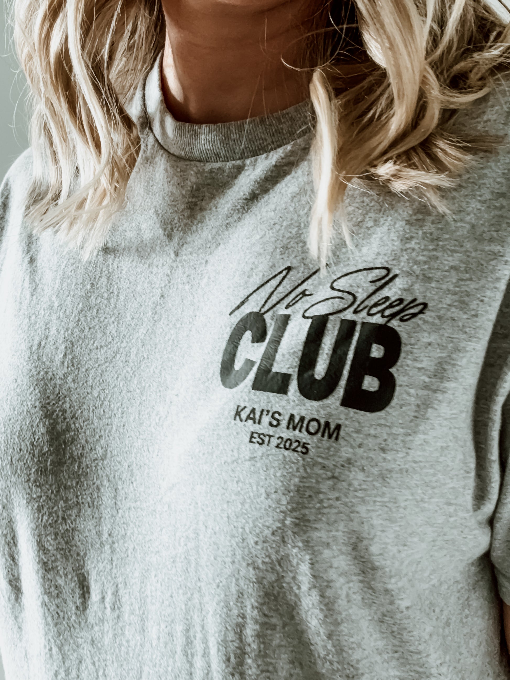 Gray sweatshirt with 'No Sleep Club KAI'S MOM EST 2025' text