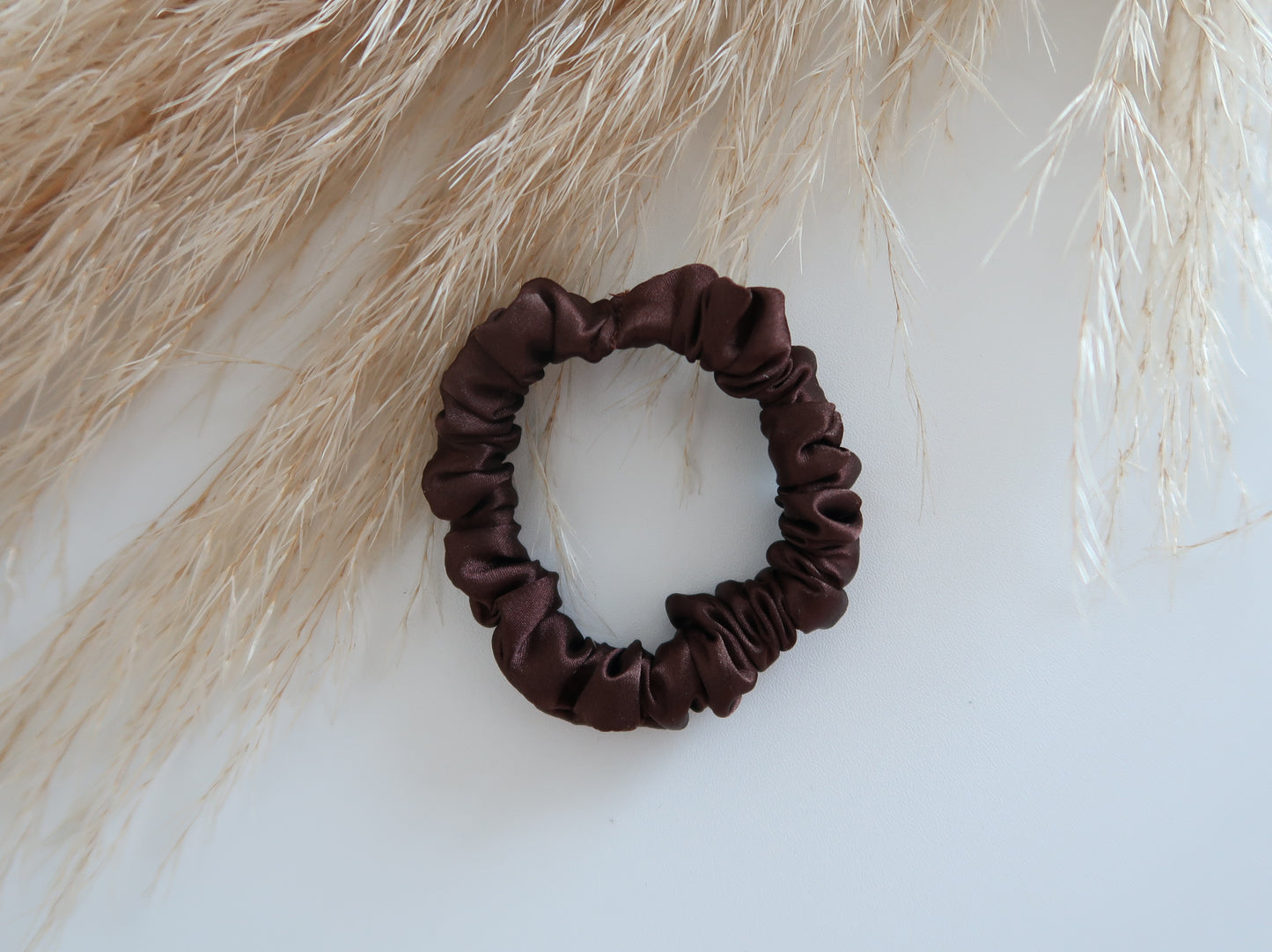 Brown scrunchie on a light background with dried grasses