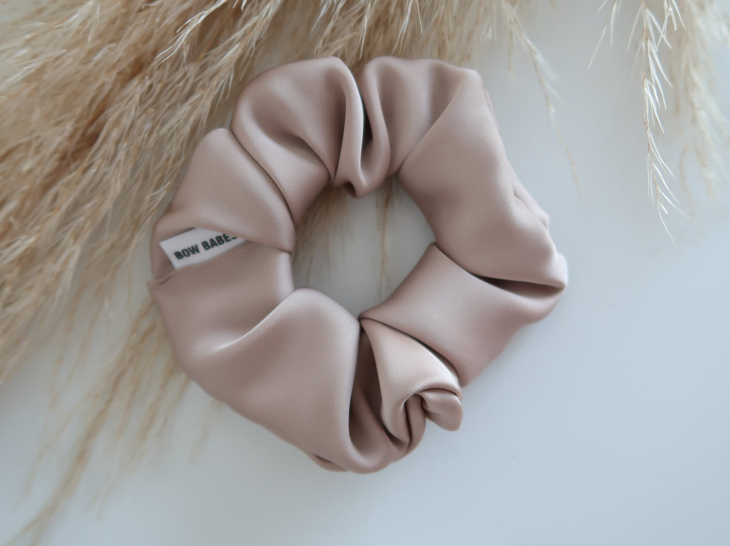 Pink scrunchie with a brand label on a light background