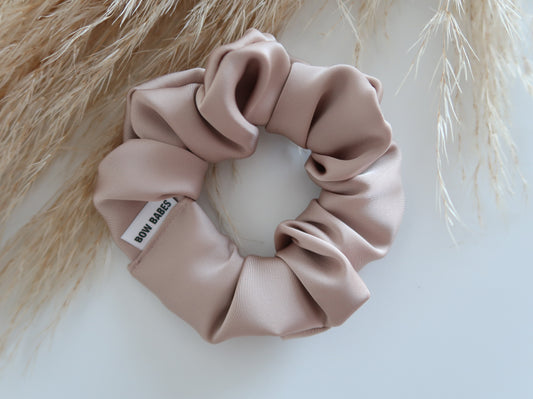 Champagne Pink scrunchie with a brand label on a light background