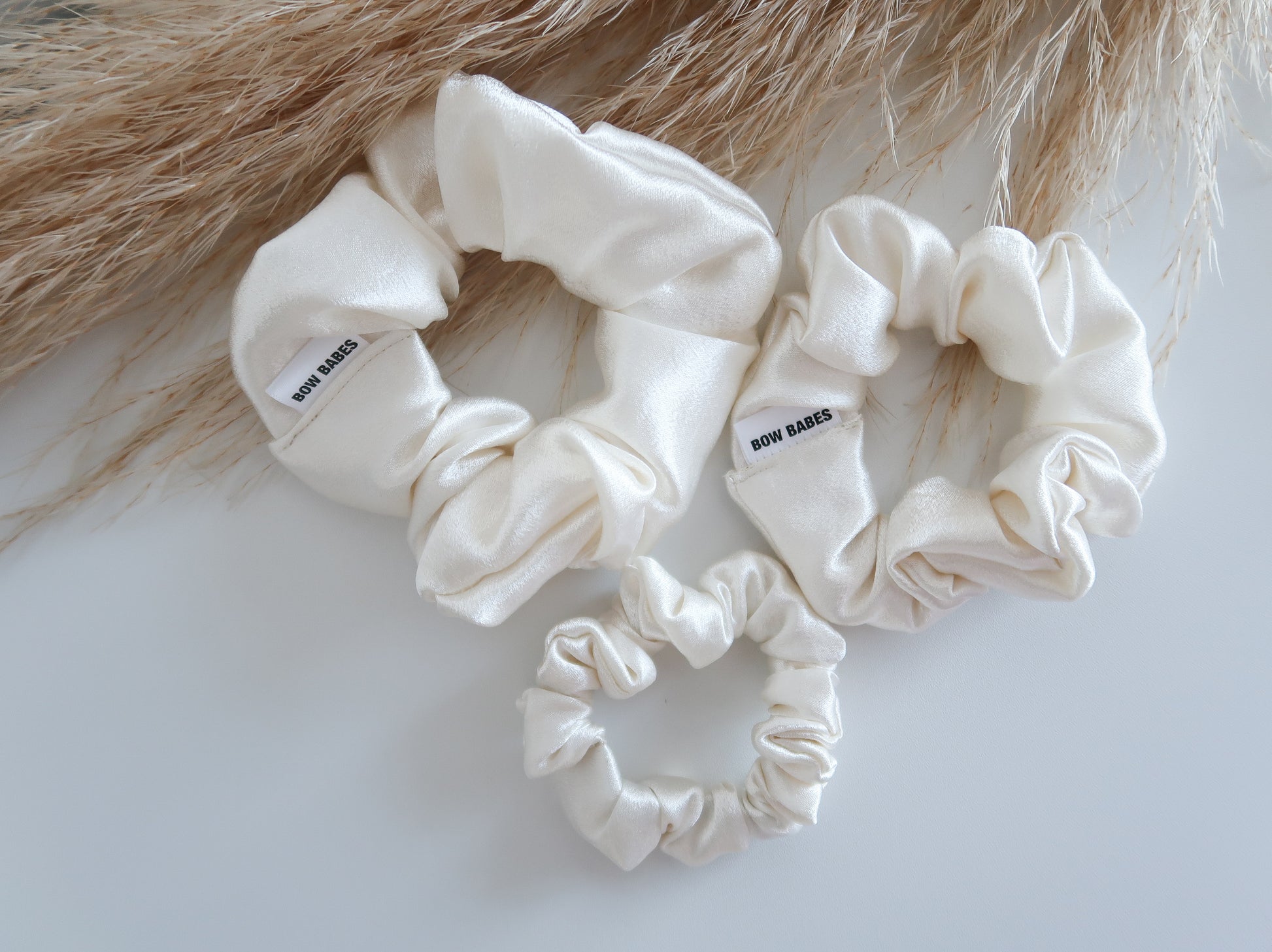 Set of cream-colored scrunchies on a textured surface