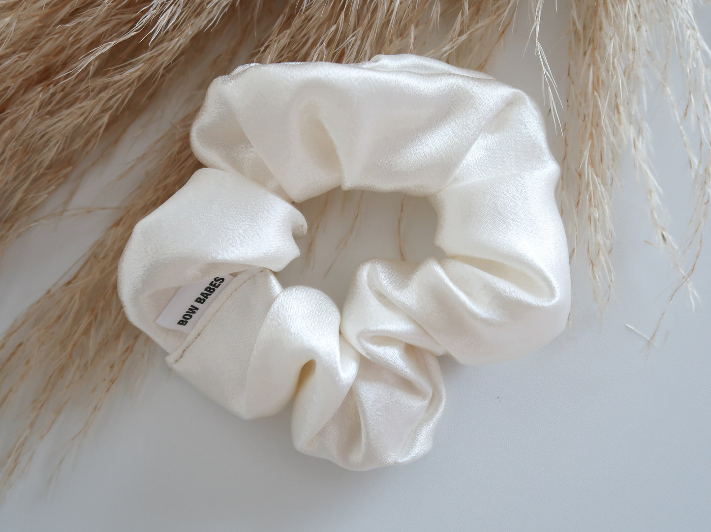 White scrunchie on a textured surface with blurred hair in the background