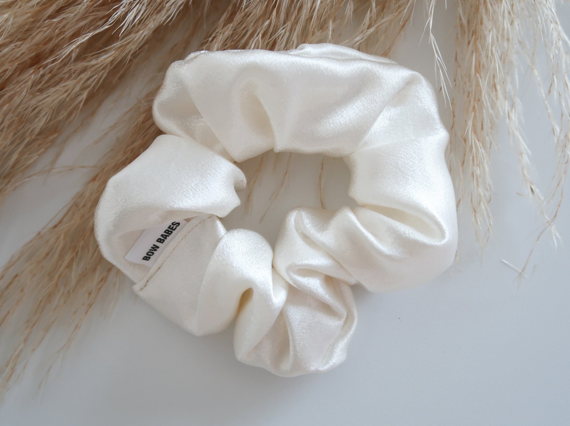 White scrunchie on a textured surface with blurred hair in the background
