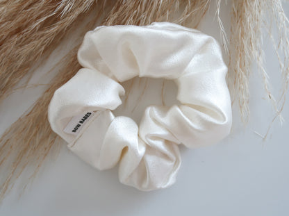White scrunchie on a textured surface with blurred hair in the background