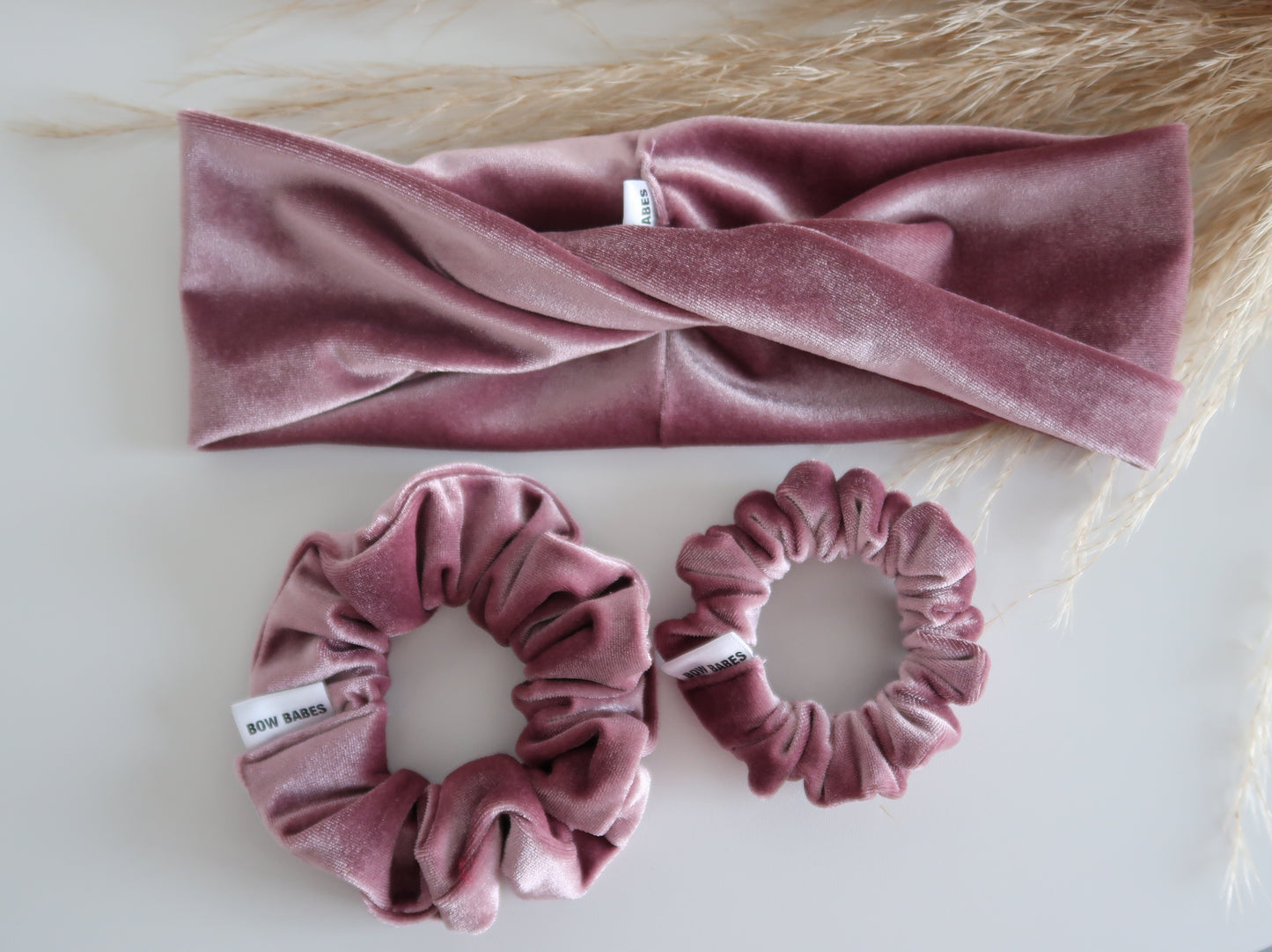 Pink velvet headband and scrunchies on a light background