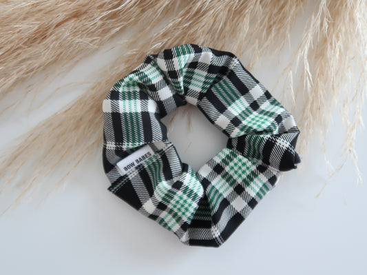 Plaid scrunchie on a white surface with a blurred natural background