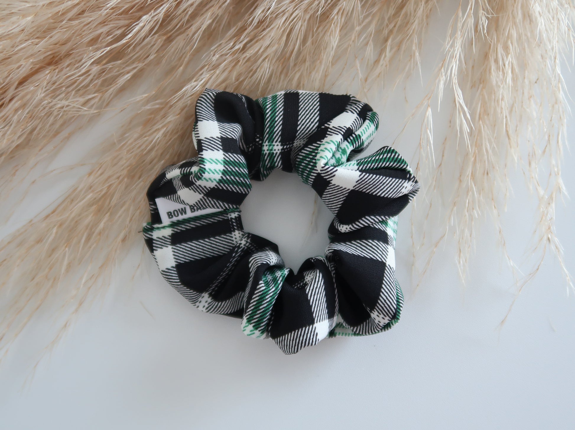 Plaid scrunchie on a white surface with a blurred natural background