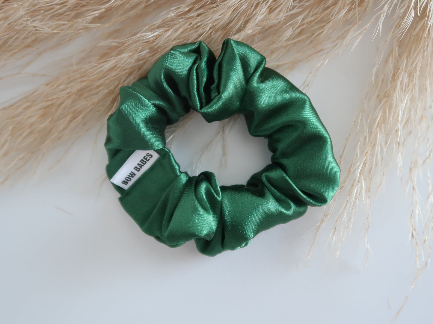 Green satin scrunchie with a label on a light background