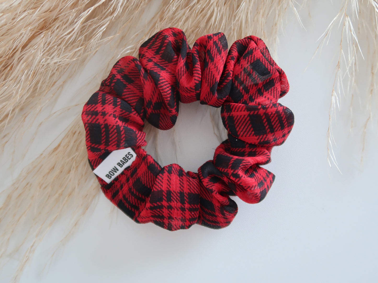 Red and black plaid scrunchie with a visible brand label on a light background
