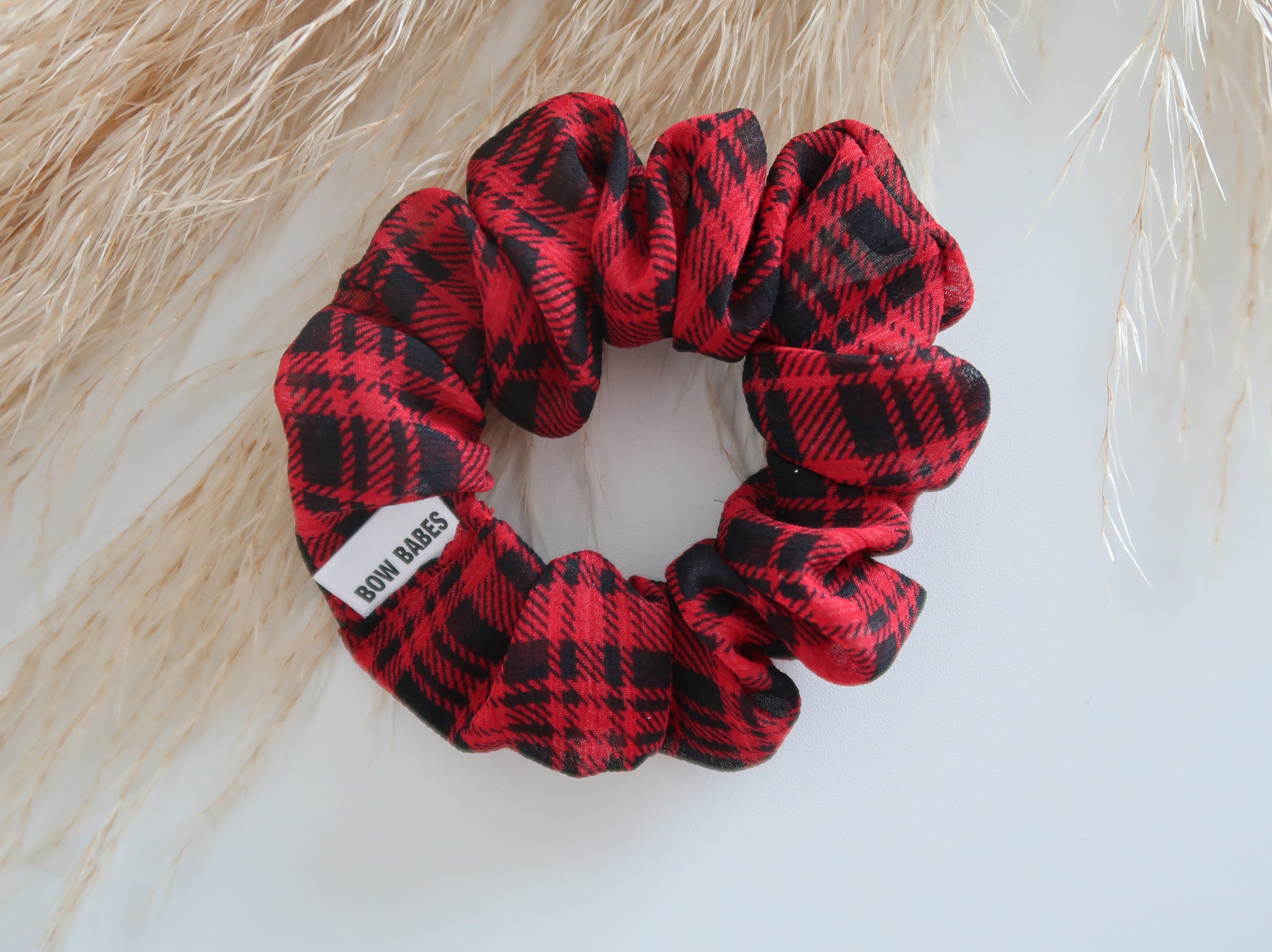 Red and black plaid scrunchie with a visible brand label on a light background