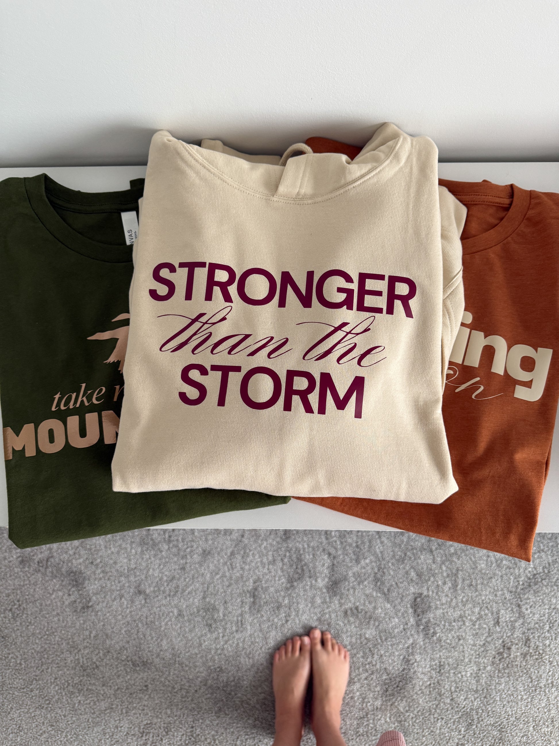 Three t-shirts with motivational phrases on a flat surface.