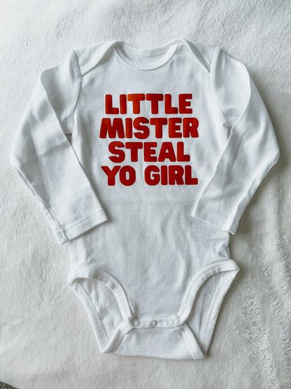 White baby onesie with red text on a light gray background