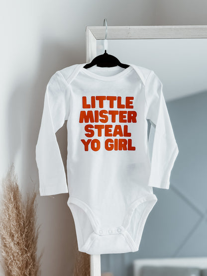 White baby onesie with red text on a hanger against a neutral background
