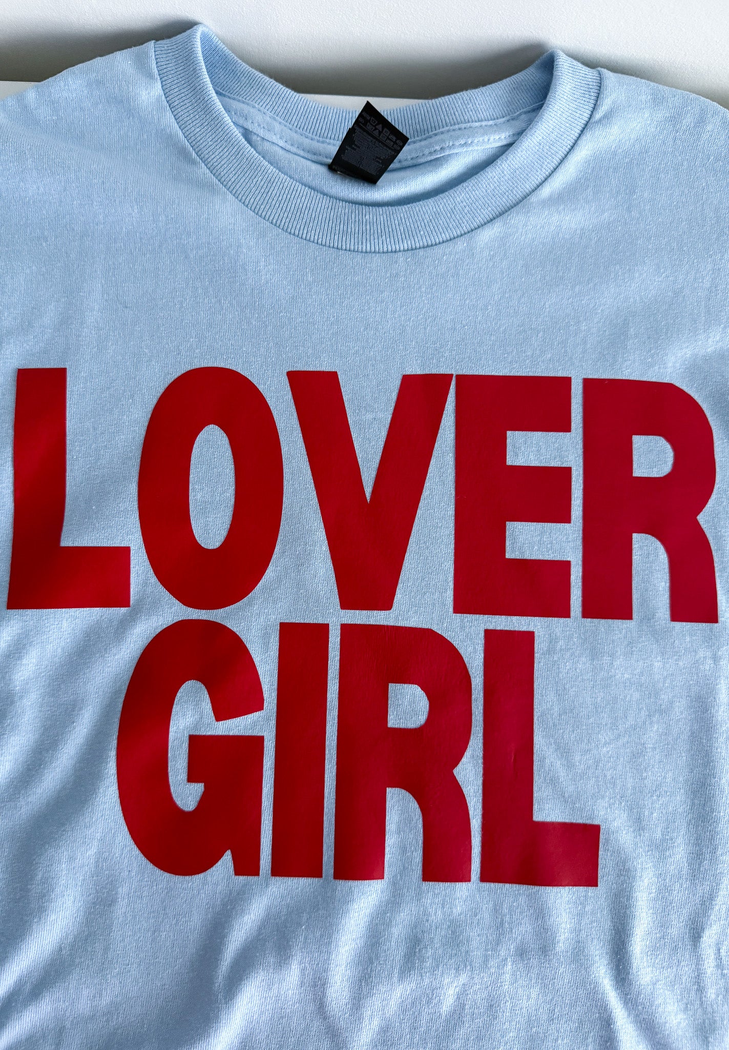 Light blue t-shirt with red text 'LOVER GIRL' on a white background
