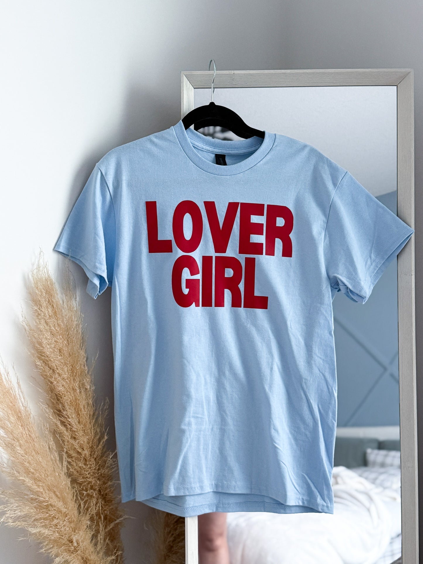 Light blue t-shirt with 'LOVER GIRL' text in red on a hanger.