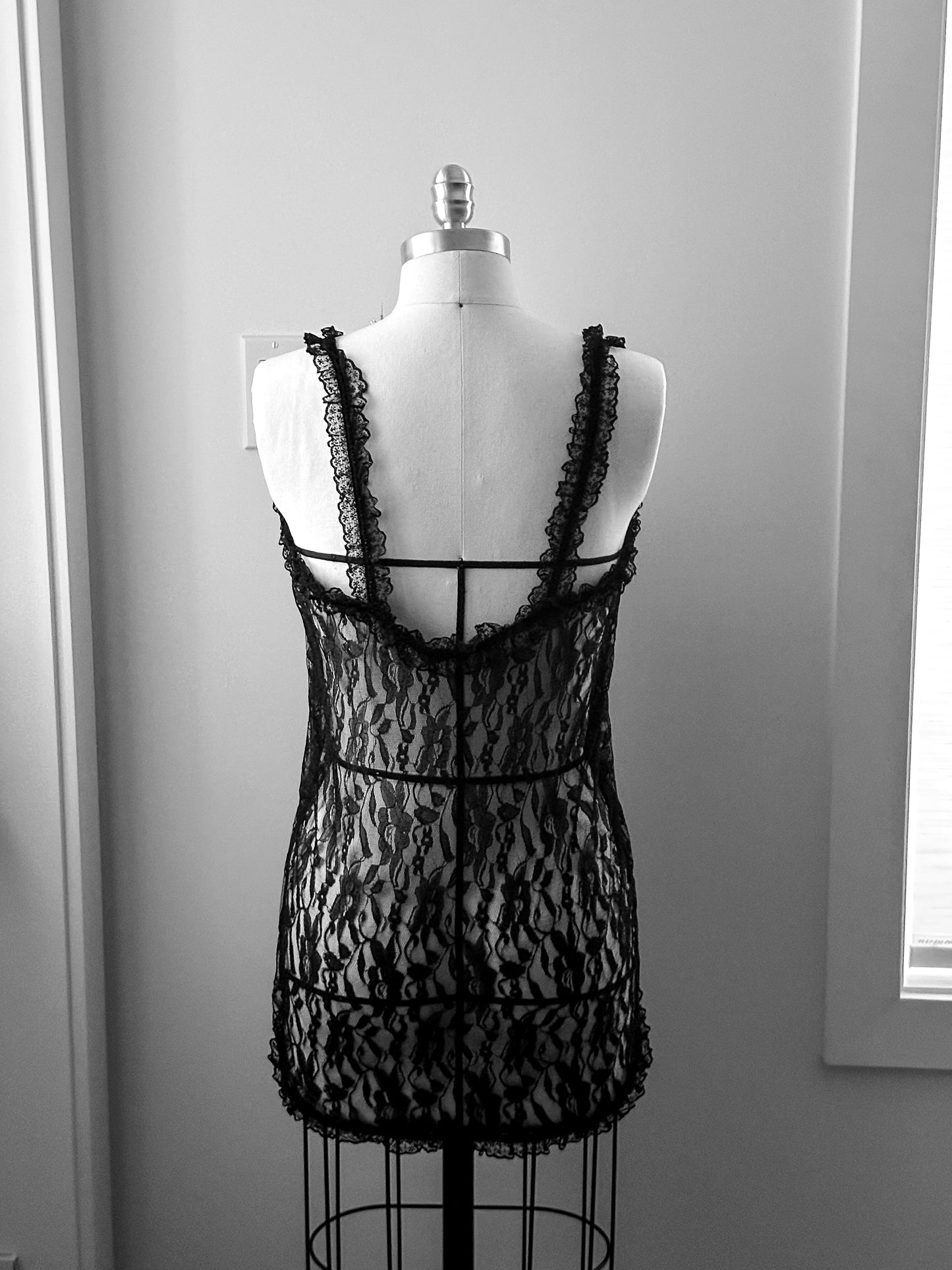 Black lace dress on a mannequin against a gray wall