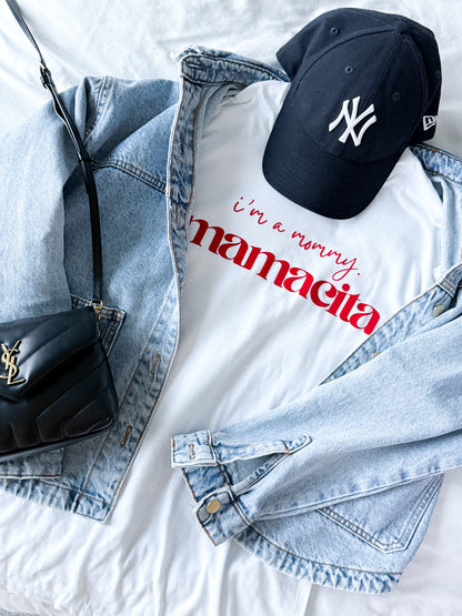 White t-shirt with red text, denim jacket, black cap, and black handbag on a light background