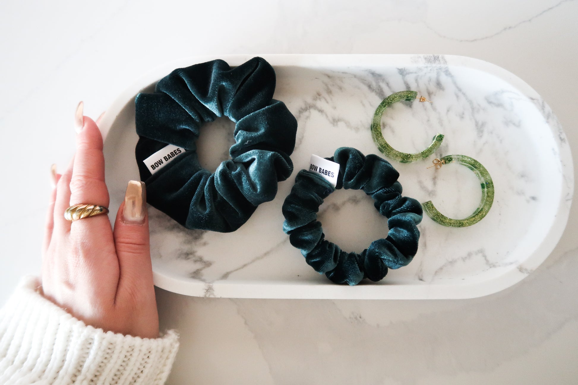 Oversized green sparkly hoop earrings made of resin paired with emerald green velvet scrunchies