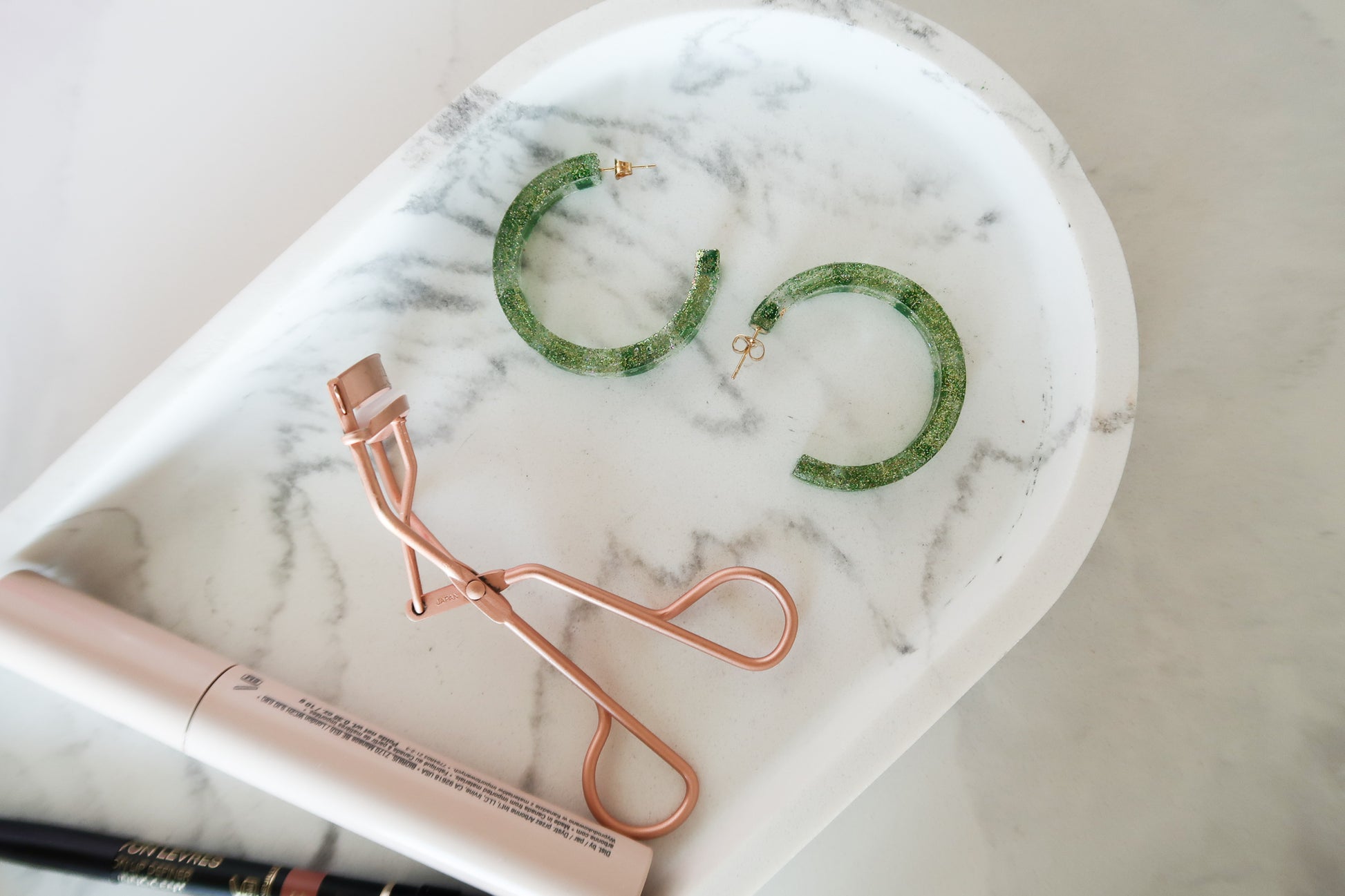 Mascara, lash curler & sparkly green hoop earrings made of resin