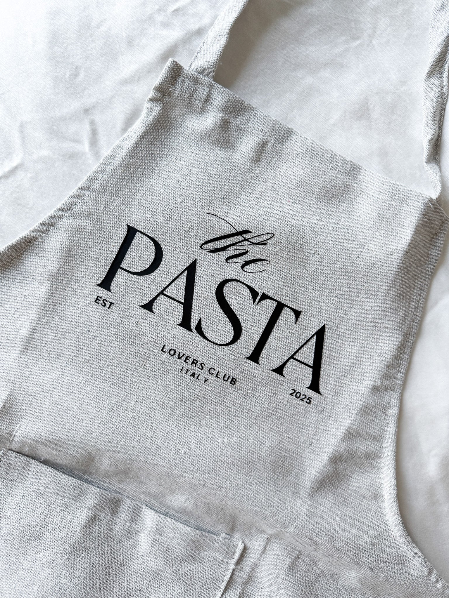 Gray apron with 'the PASTA LOVERS CLUB' text on a white background