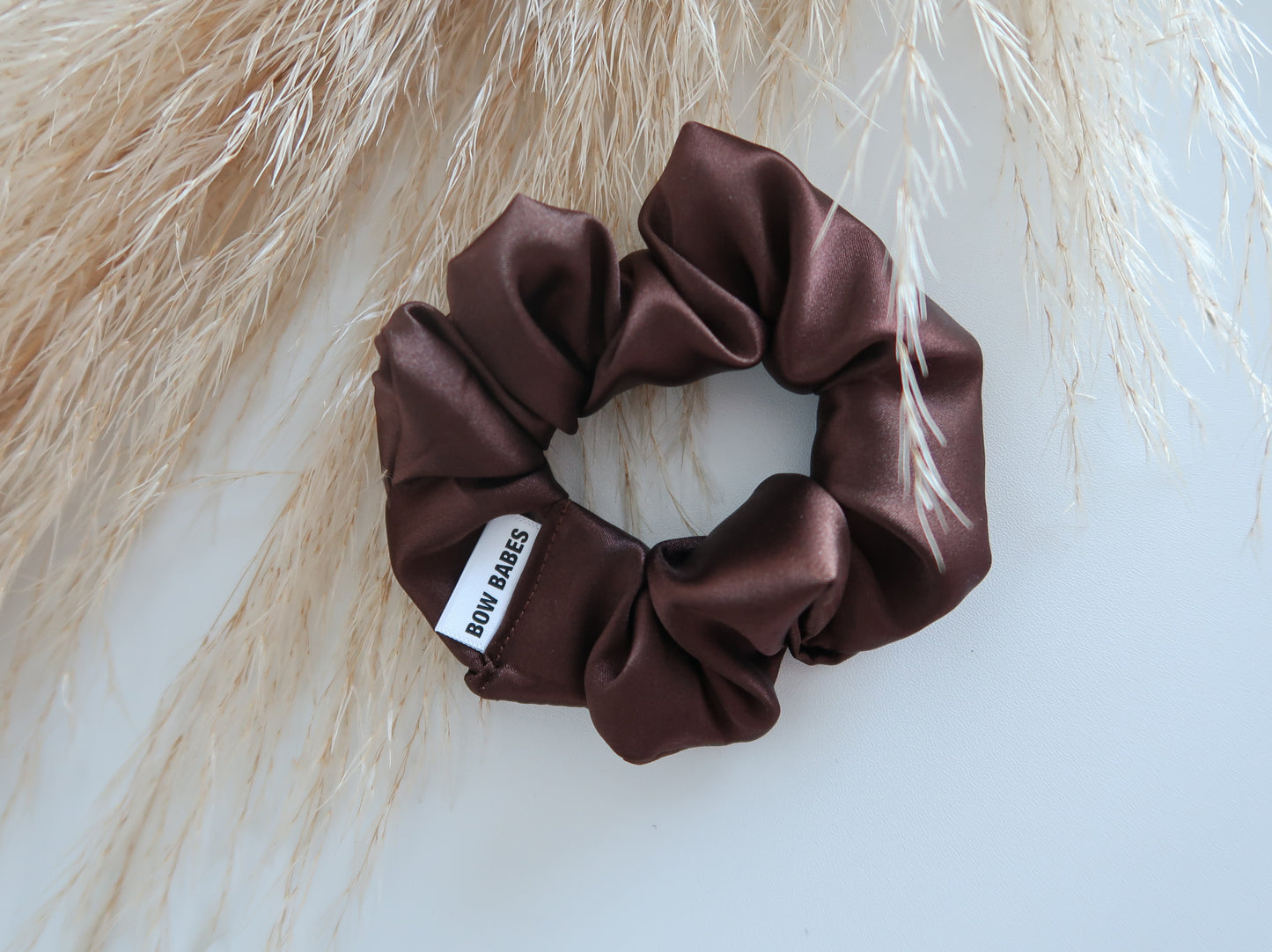 Brown satin scrunchie with a label on a light background