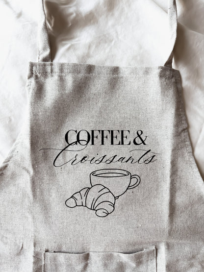Light gray apron with 'Coffee & Croissants' text and graphics on a white background