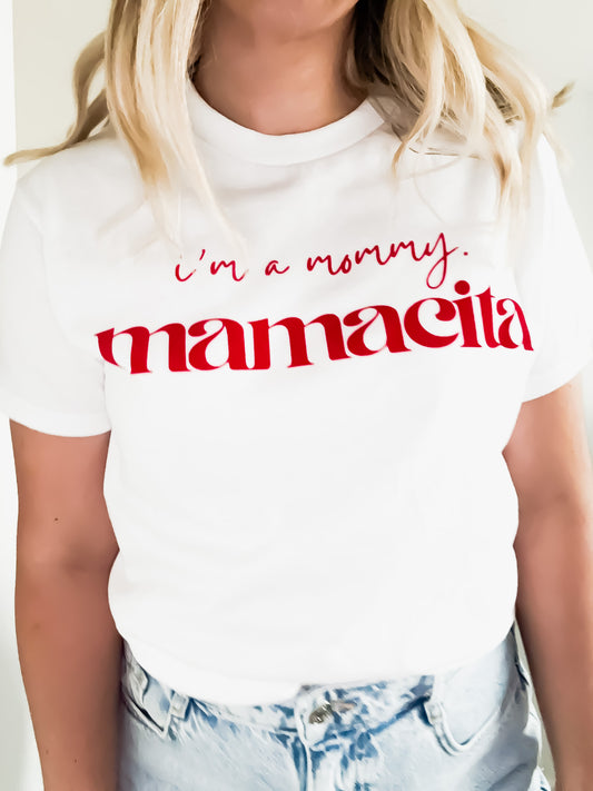 White t-shirt with red text 'i'm a mommy. mamacita' worn by a person.