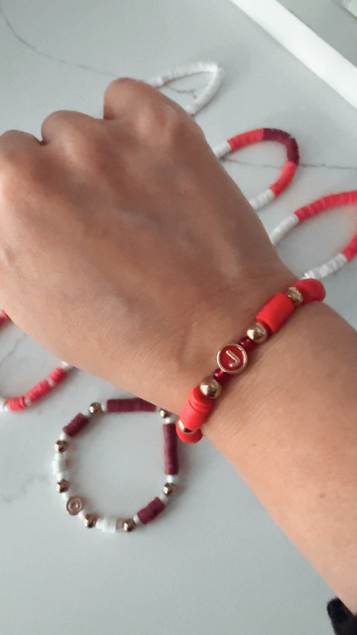 Hand wearing a red beaded bracelet on a light background