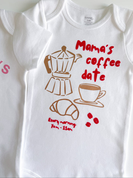 White baby onesie with coffee-themed graphics and text on a white background