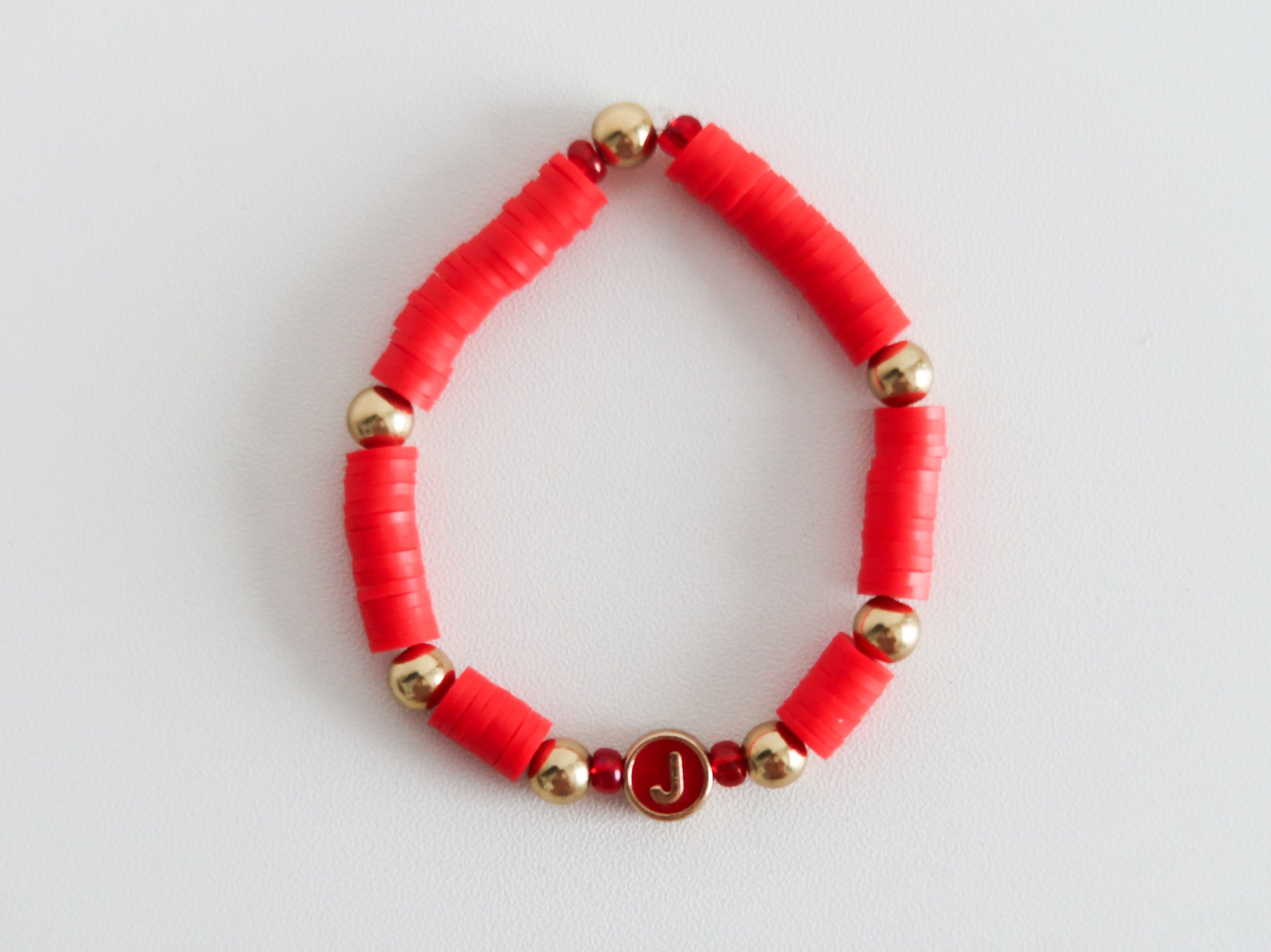 Red beaded bracelet with gold accents on a light gray background