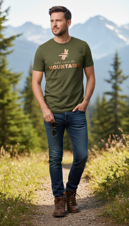 Man wearing a green t-shirt with 'Take me to the Mountains' text, standing in a mountainous landscape.